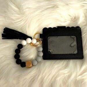 Black Wristlet with gold accents and white, gray and black beads on wrist.